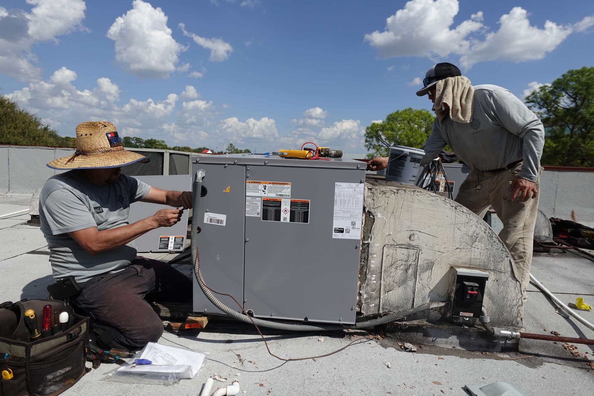 Two technicians performing rooftop HVAC maintenance